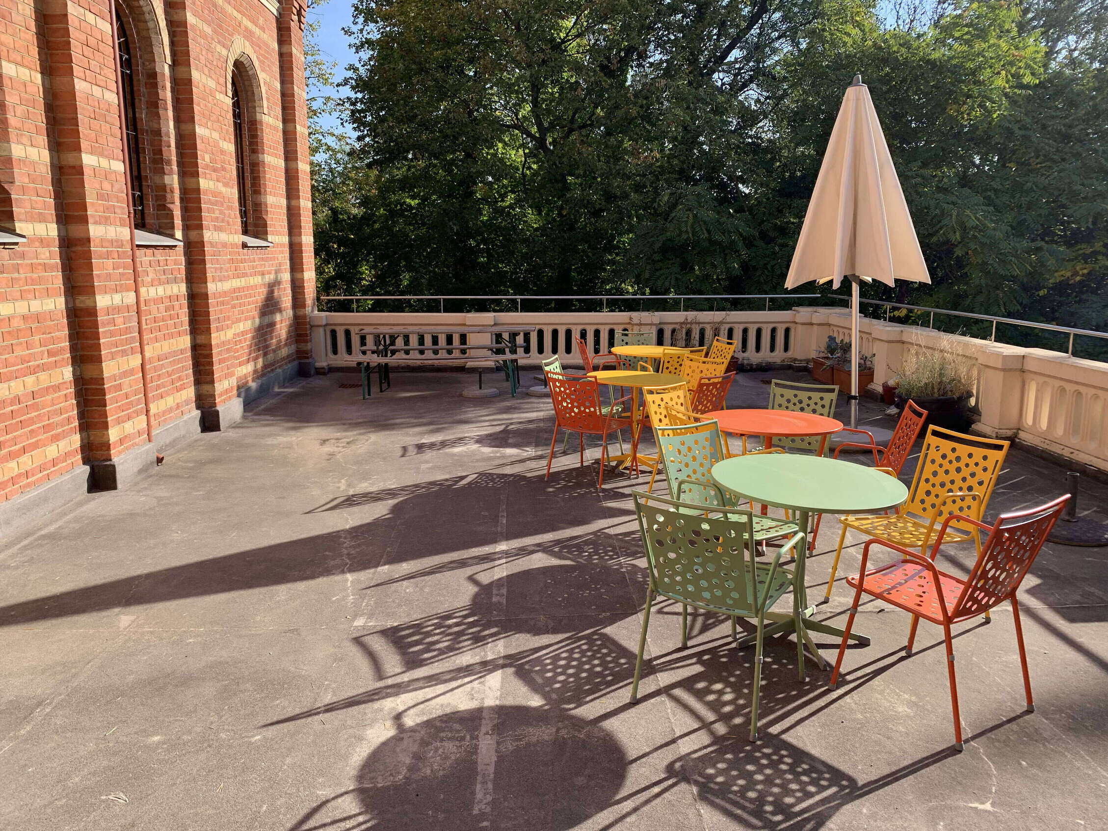 Eine Terrasse mit einigen bunten Stühlen sowie Tischen und Sonnenschirmen